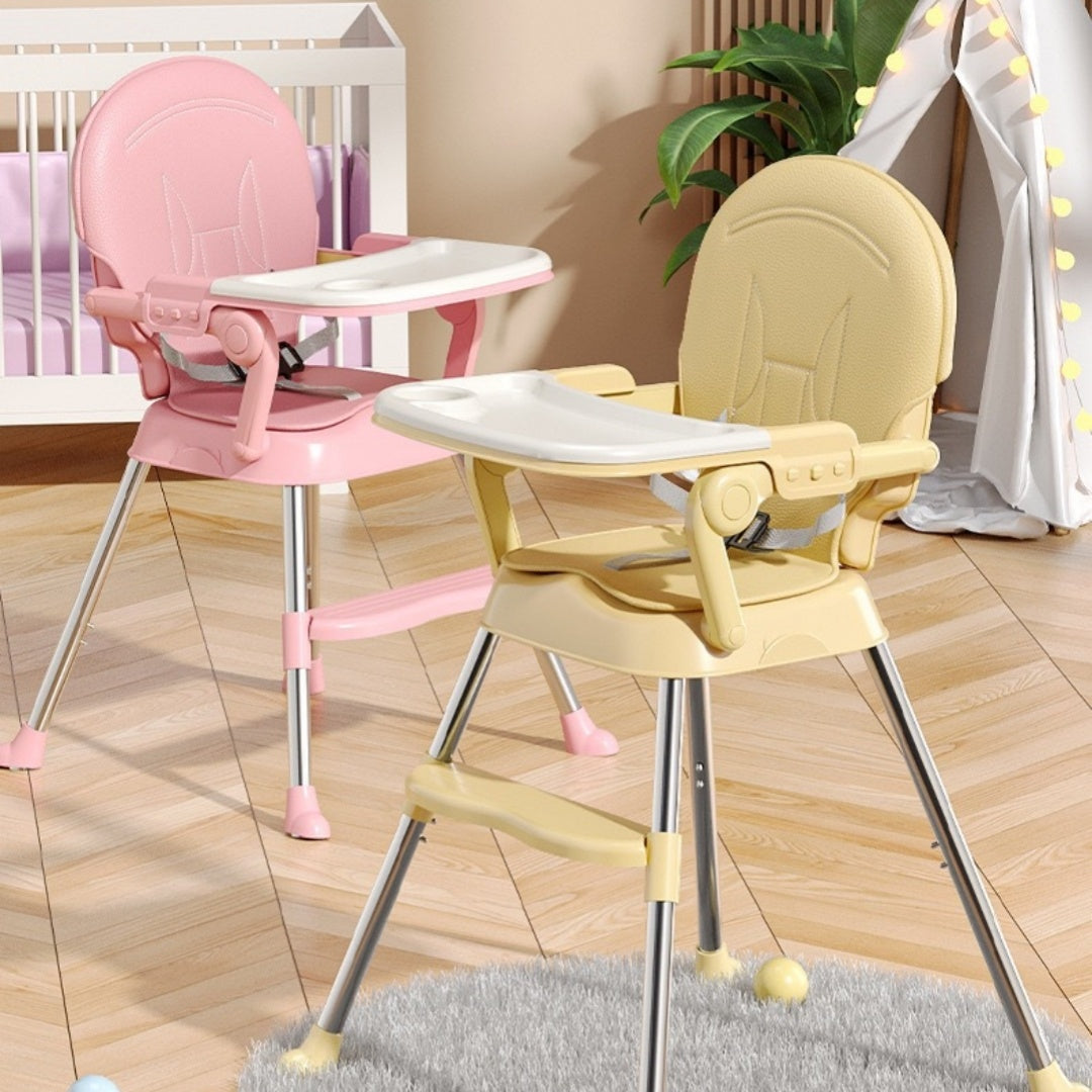 Two high chairs, one pink and one yellow, on a wooden floor.