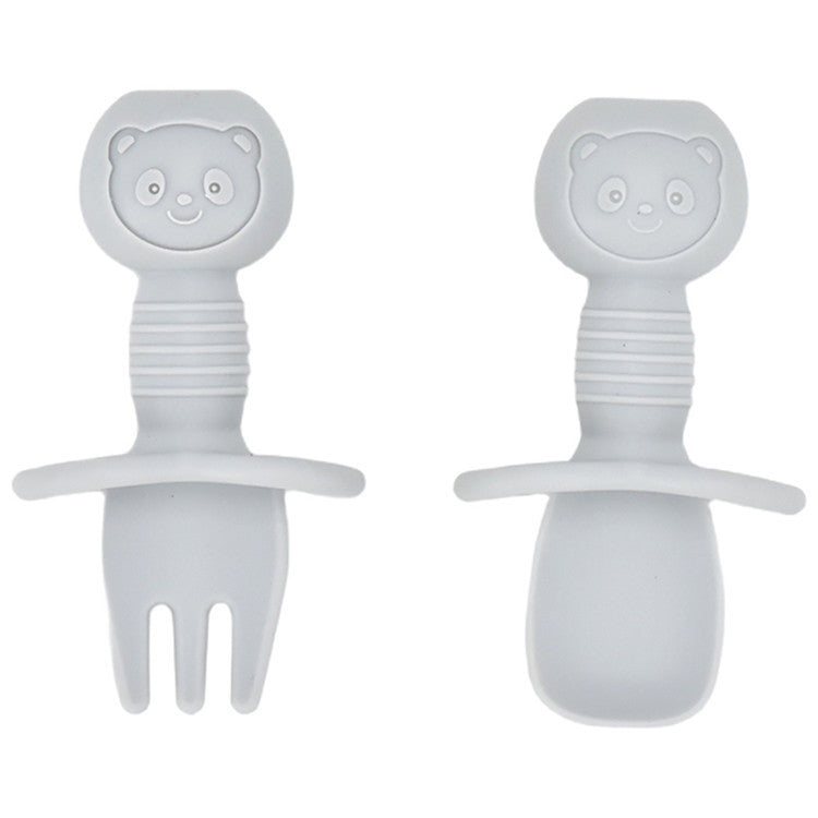Two white baby utensils with bear faces on a white background