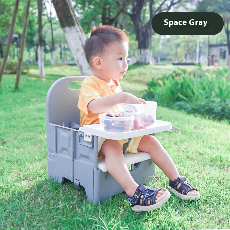 Child sitting on a portable chair with a tray outdoors, labeled 'Space Gray'.