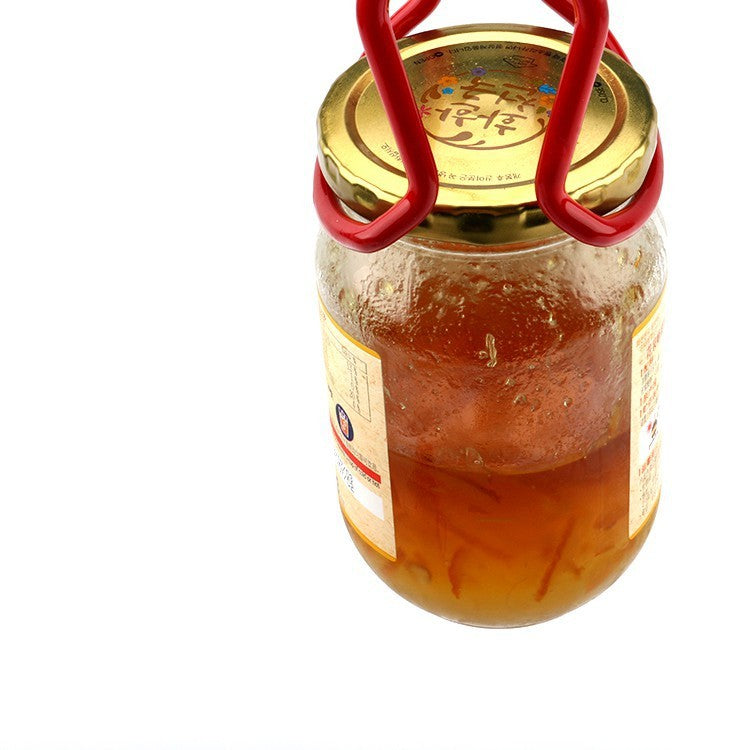 Jar of honey with a gold lid and red handles on a white background