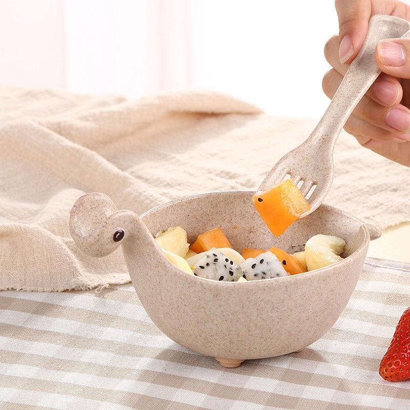 Bowl shaped like a duck with fruit inside, being fed by a fork.