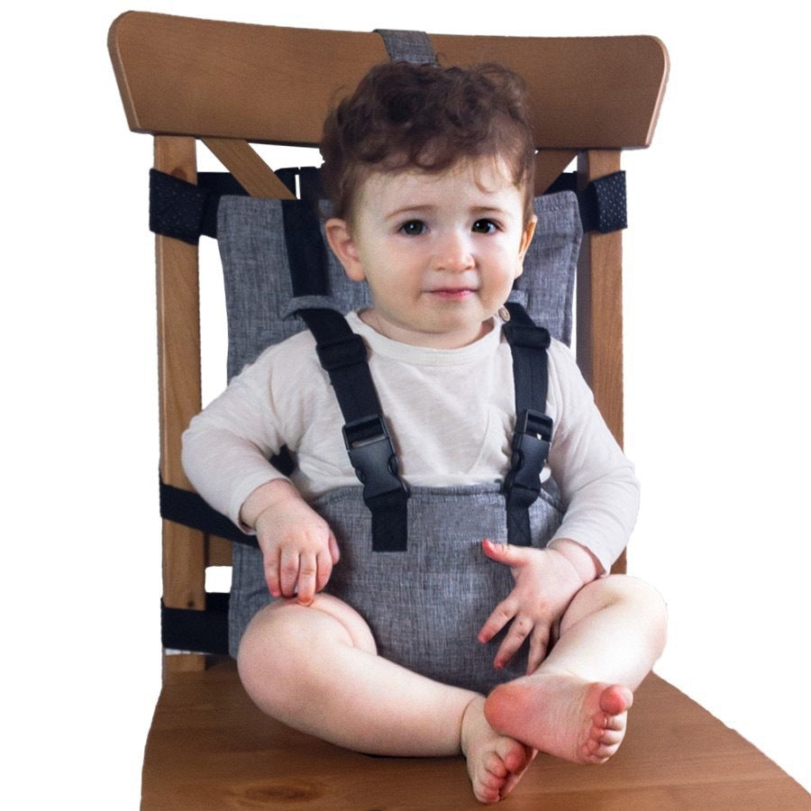 Child sitting in a high chair with a safety harness on a white background