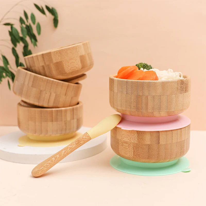 Stackable bamboo bowls with a pink base and green lid on a light background