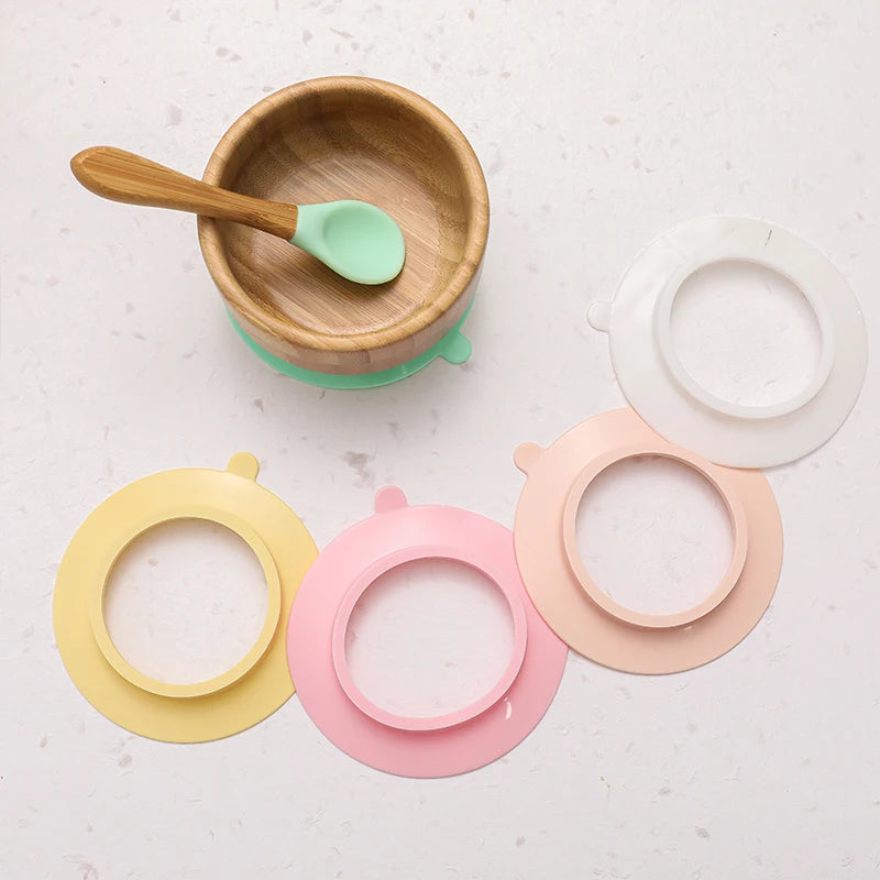 Wooden bowl with a spoon and colorful silicone lids on a light surface