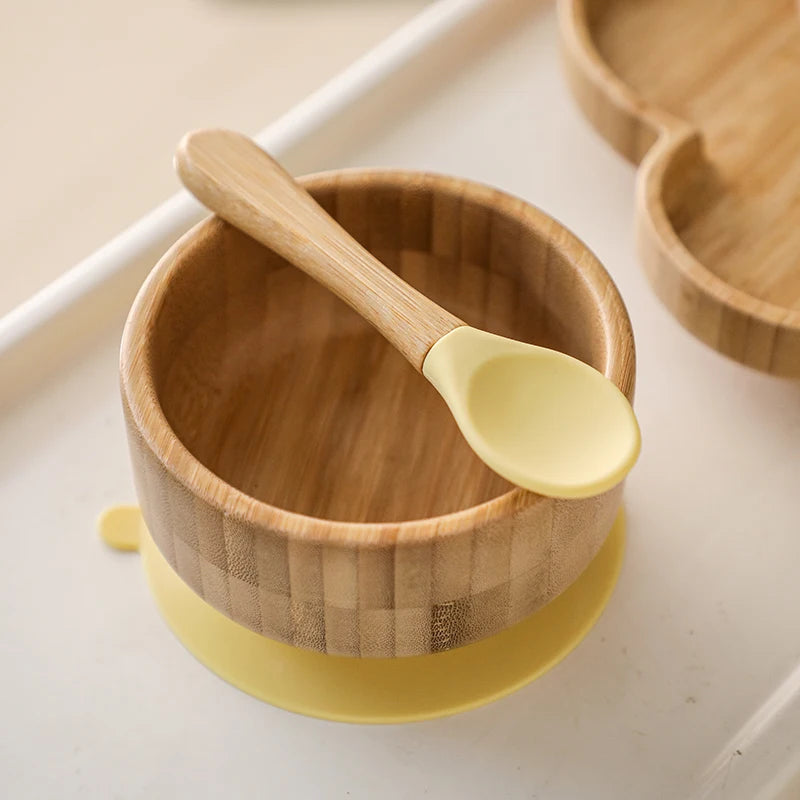 Wooden bowl with yellow base and spoon on a light background