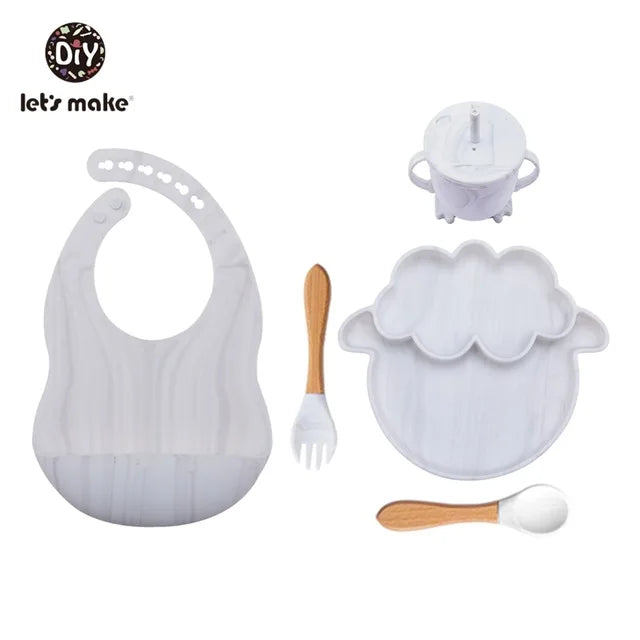 Baby feeding set with bib, plate, cup, fork, and spoon on a white background