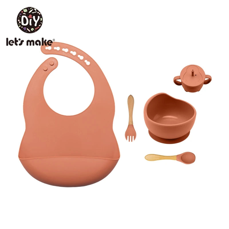 Baby feeding set with bib, bowl, cup, and utensils on a white background