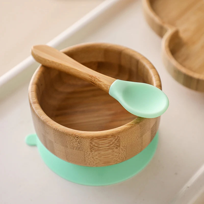 Wooden bowl with a green silicone base and spoon on a light background
