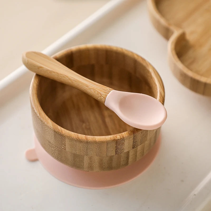 Wooden bowl with pink base and spoon on a white surface