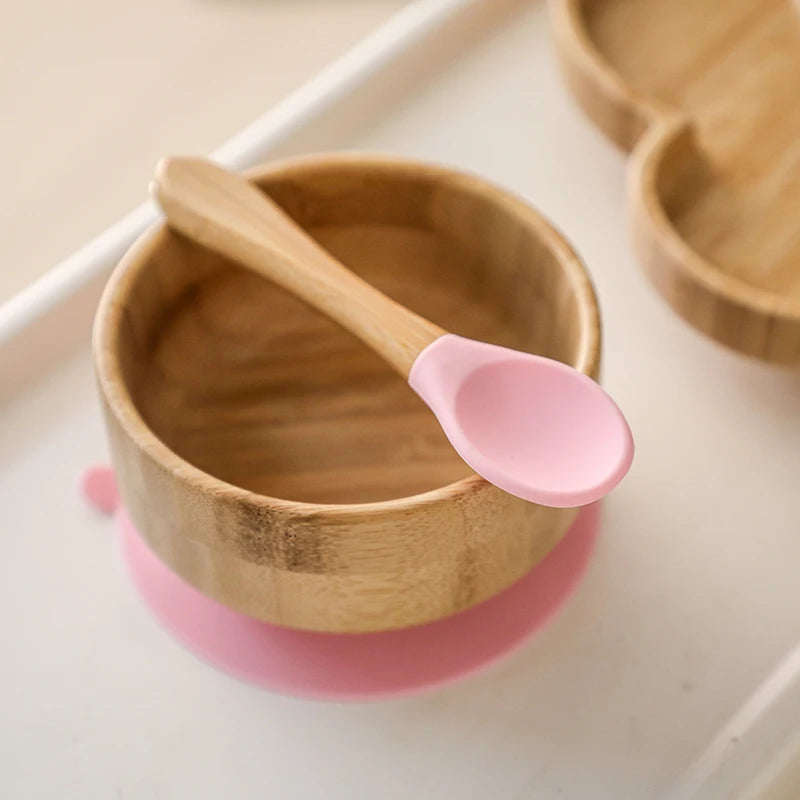 Wooden bowl with a pink spoon on a white surface