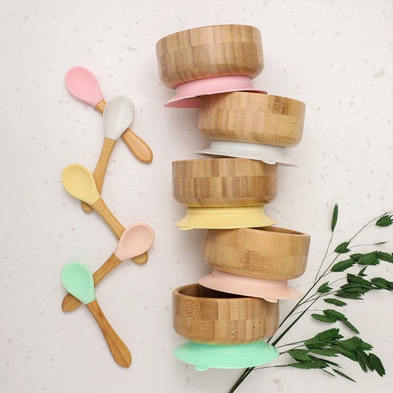 Stack of bamboo bowls with colorful lids and wooden spoons on a light background
