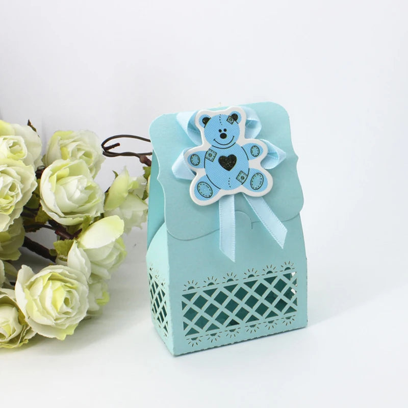 Light blue gift box with teddy bear design and ribbon, surrounded by white flowers on a white background