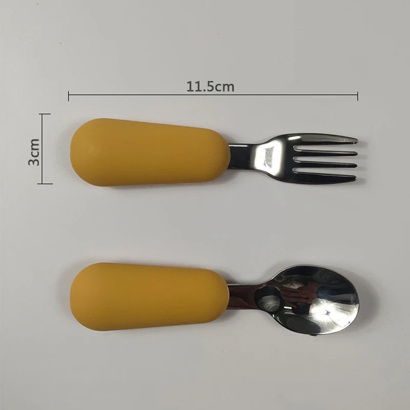 Children's fork and spoon set with yellow handles on a gray background