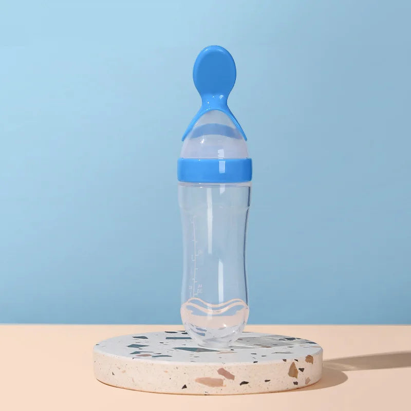 Baby bottle with blue cap on a round stone platform against a light blue background
