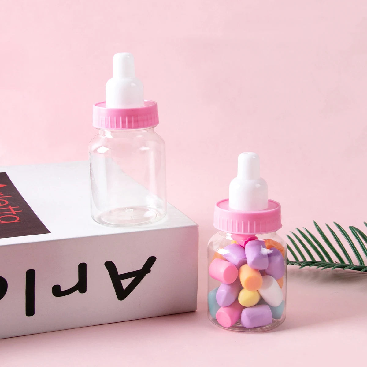 Clear bottle with pink cap filled with colorful candies on a pink background