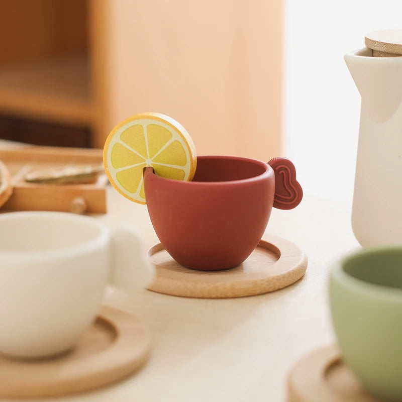 Ceramic teacup with lemon slice on a wooden coaster, surrounded by other ceramic items.