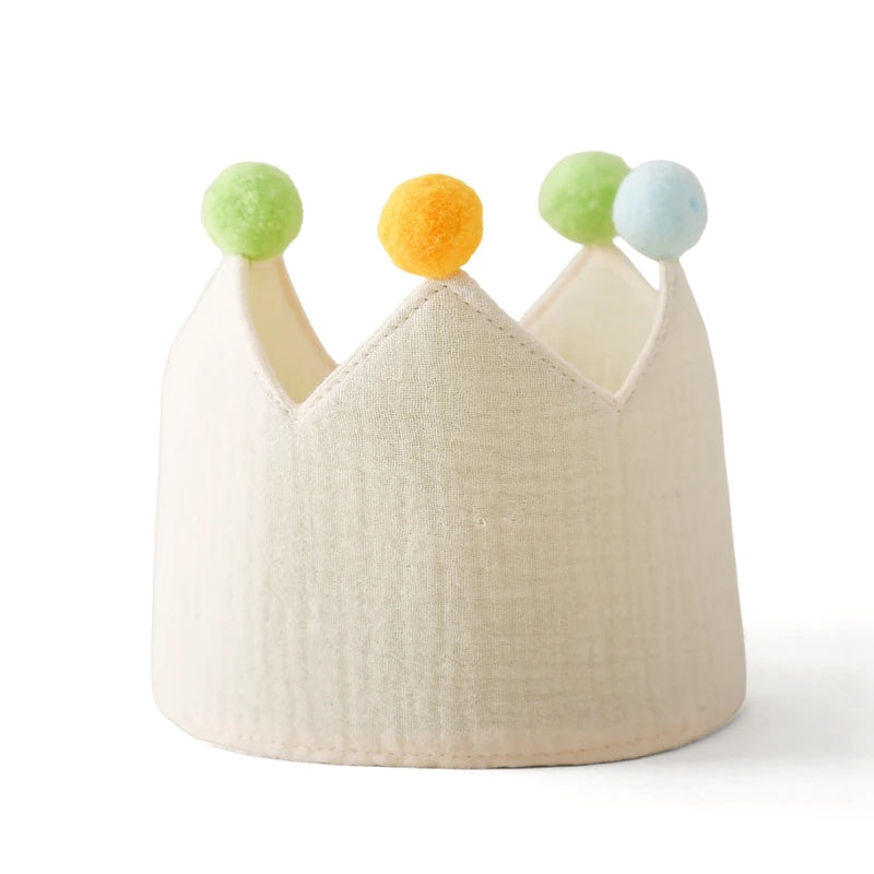 Beige crown with colorful pom-poms on a white background