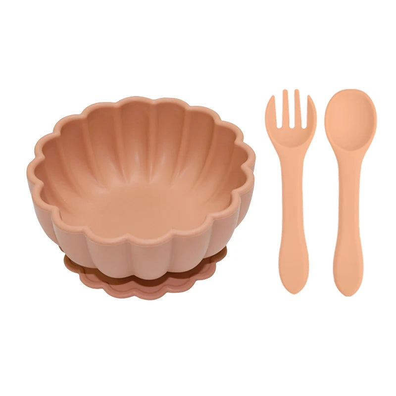 Set of peach-colored bowl, fork, and spoon on a white background