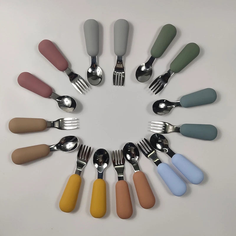 Set of colorful cutlery with handles arranged in a circular pattern on a light gray background.