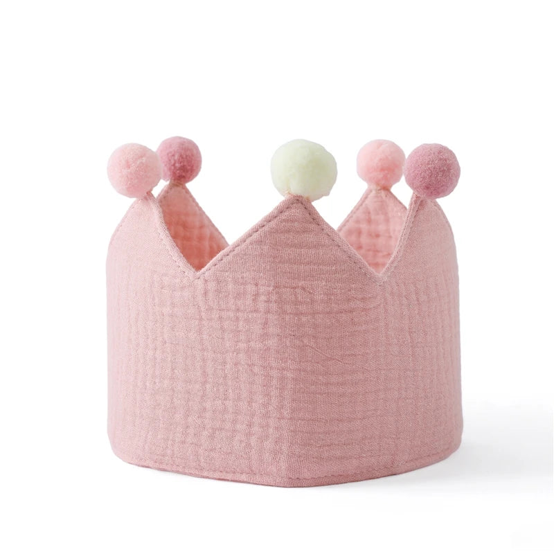 Pink textured crown with colorful pom-poms on a white background