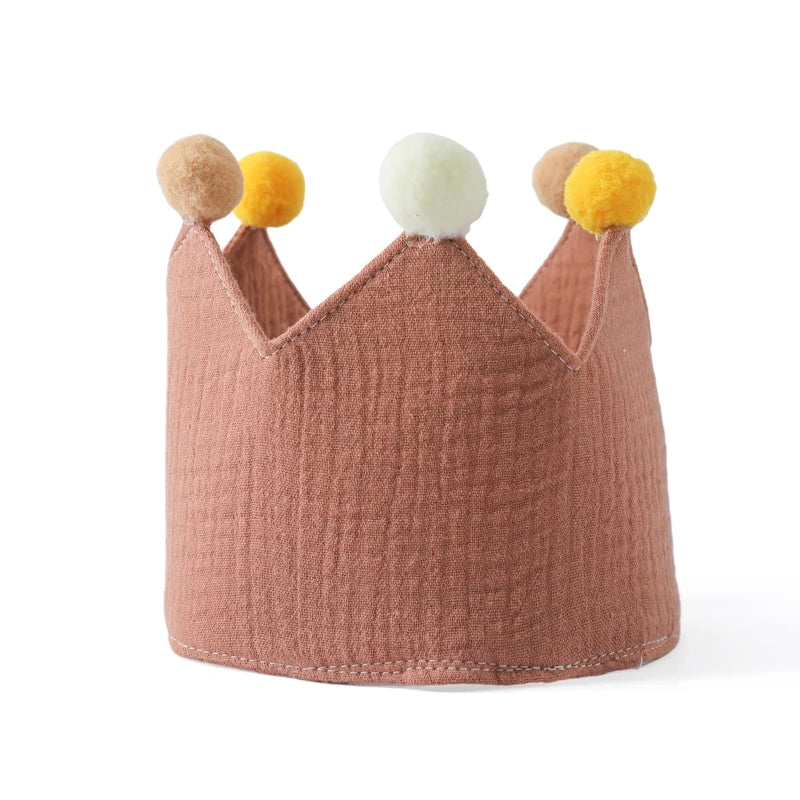 Pink crown with colorful pom-poms on a white background