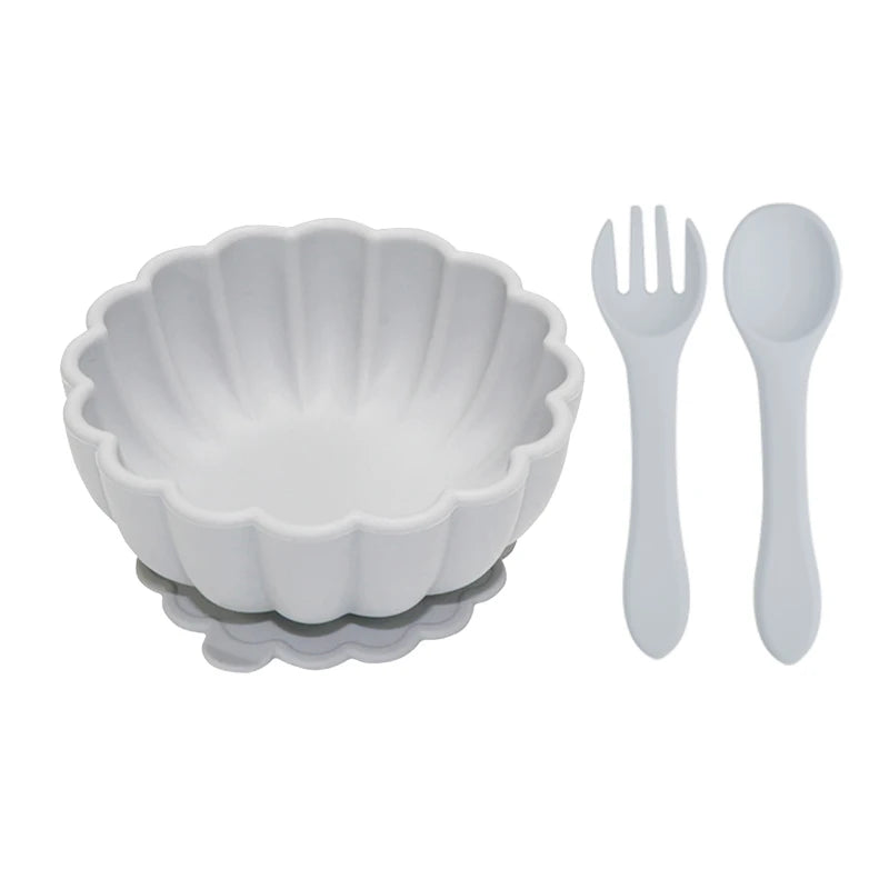 White scalloped bowl with matching fork and spoon on a white background