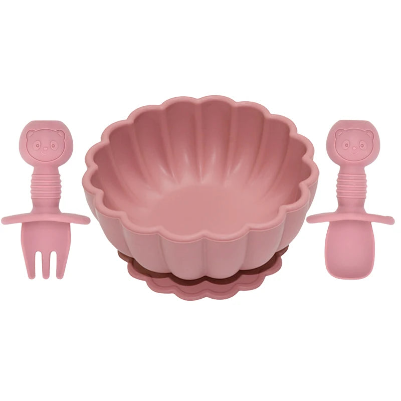 Pink children's bowl set with fork and spoon on a white background