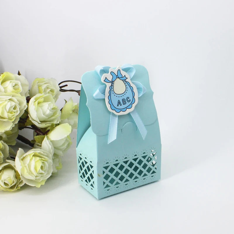 Light blue gift box with decorative bow and baby bib design, surrounded by white flowers on a light gray background