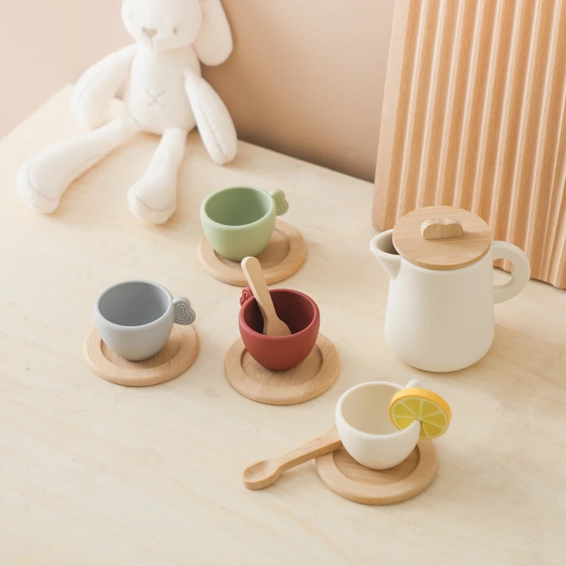 Set of ceramic tea cups and teapot with wooden accents on a light surface.