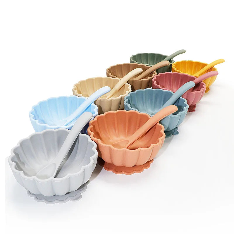 Set of colorful ceramic bowls with spoons on a white background