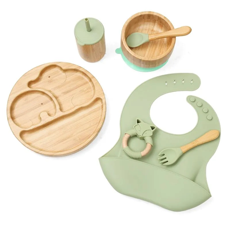Children's dining set with wooden plate, cup, bowl, and bib on a white background