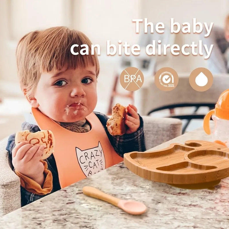 Child eating with a wooden plate and spoon, sitting at a table.