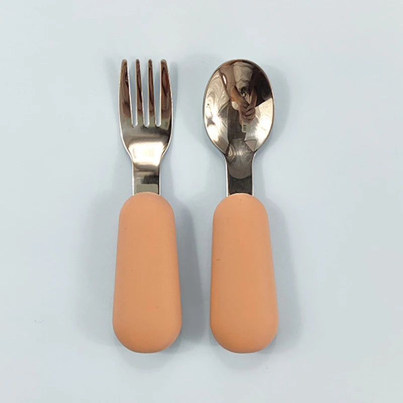 Fork and spoon set with peach-colored handles on a light gray background