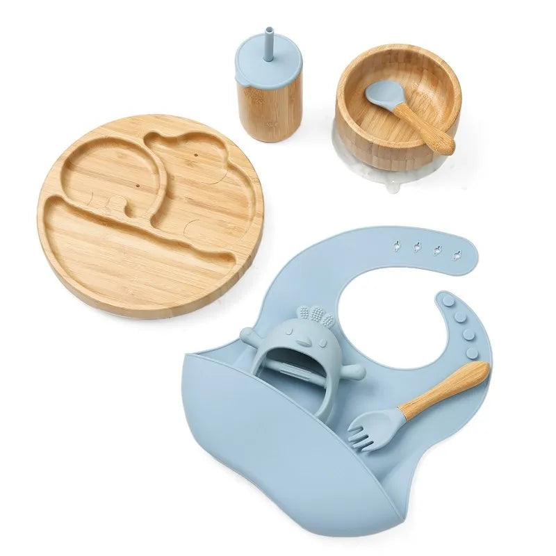 Set of wooden plate, bowl, cup, and bib with spoon on a white background