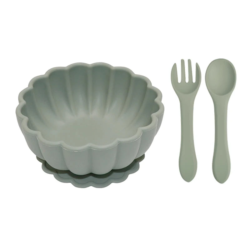Set of green ceramic bowl, fork, and spoon on a white background