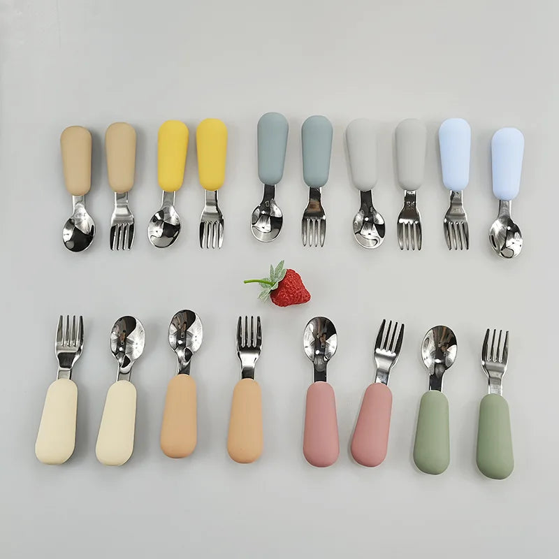 Set of colorful children's cutlery with a strawberry on a gray background
