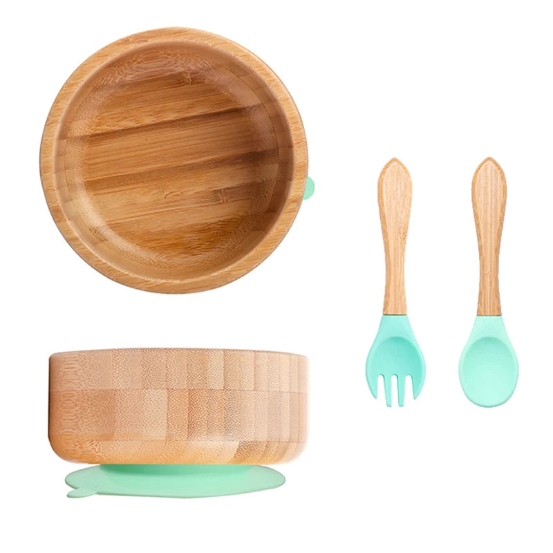 Bamboo bowl set with green silicone bases and utensils on a white background