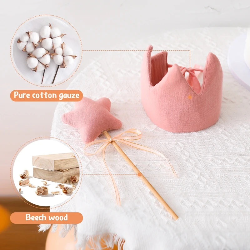 Pink baby items including a crown, pillow, and wooden toy on a white background with cotton and wood insets.