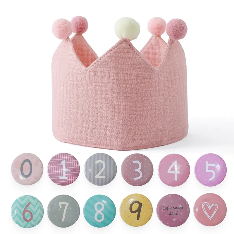 Pink children's crown with pom-pom accents on a white background