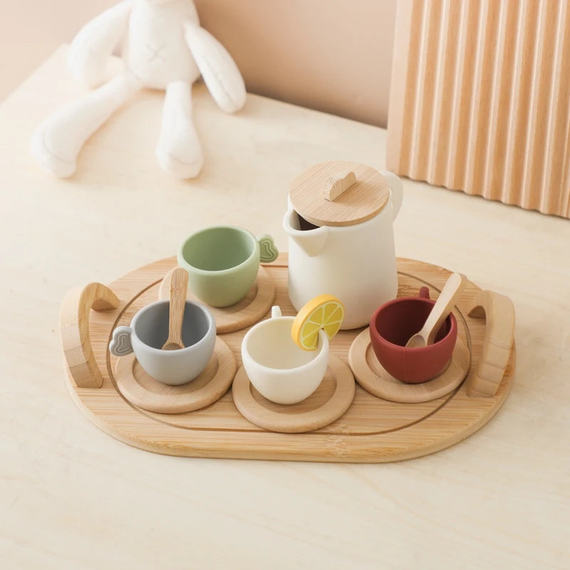 Set of ceramic cups and a teapot on a wooden tray with a lemon wedge and a white rabbit plush toy in the background.