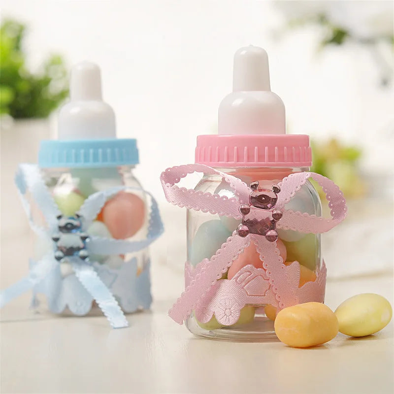 Decorative baby bottle-shaped jars with candies and ribbons on a blurred background