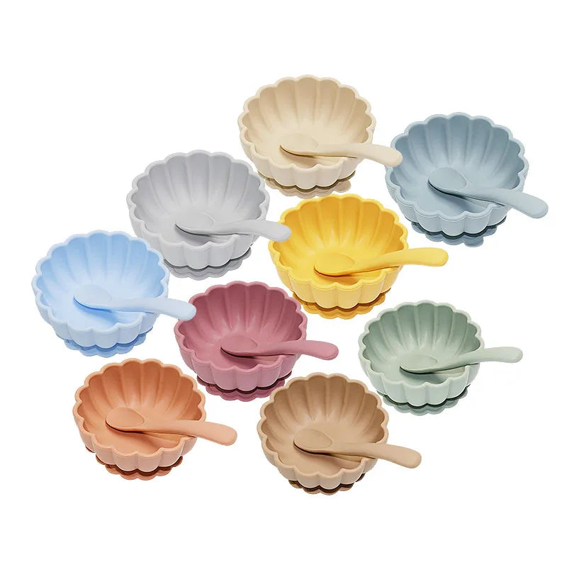 Set of colorful shell-shaped bowls with spoons on a white background
