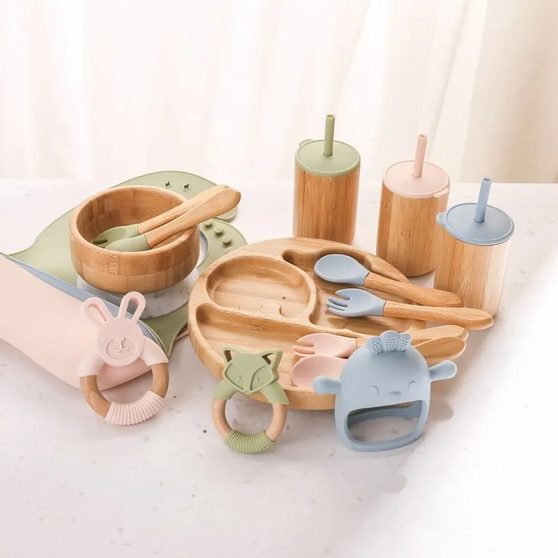 Children's tableware set with wooden and silicone items on a light background