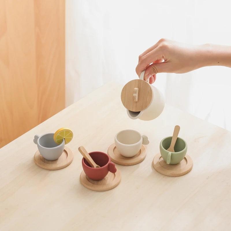 Person pouring a drink from a wooden teapot into ceramic cups on a light surface.
