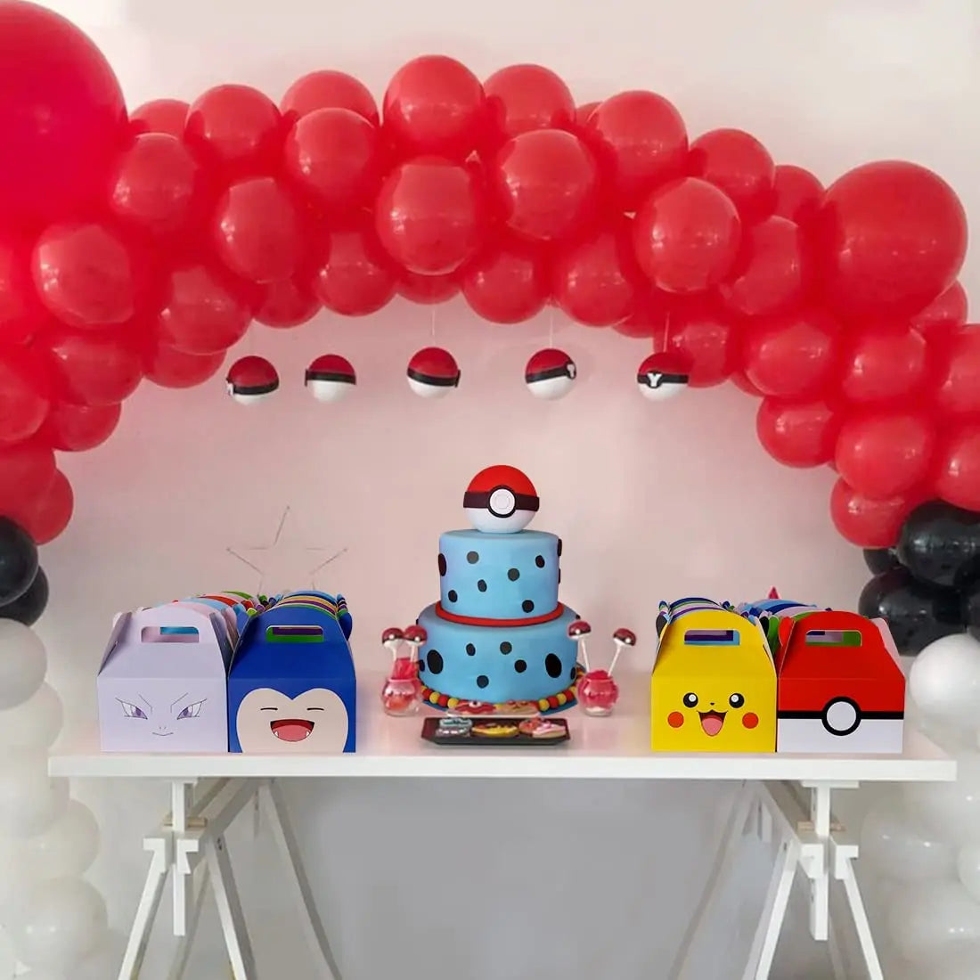 Decorative setup with red balloon arch, cake, and themed gift boxes on a white table.