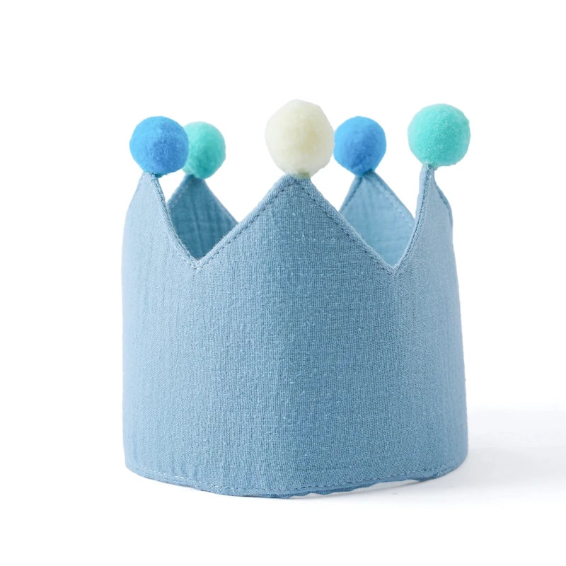 Blue children's crown with colorful pom-poms on a white background
