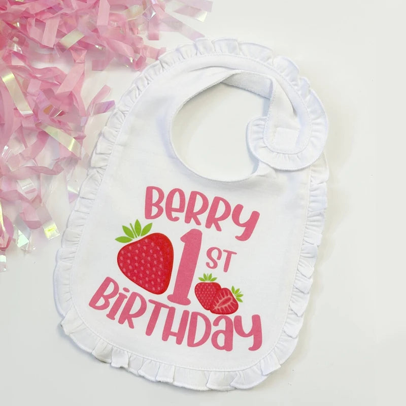 White bib with 'Berry 1st Birthday' text and strawberry graphics on a white background with pink confetti.