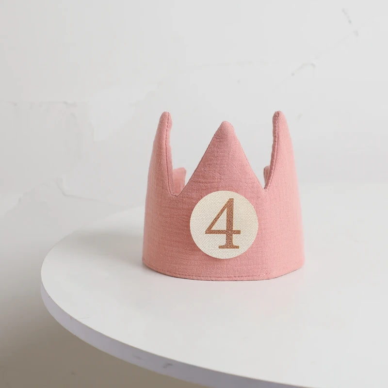 Pink children's crown with the number 4 on a white surface and light gray background