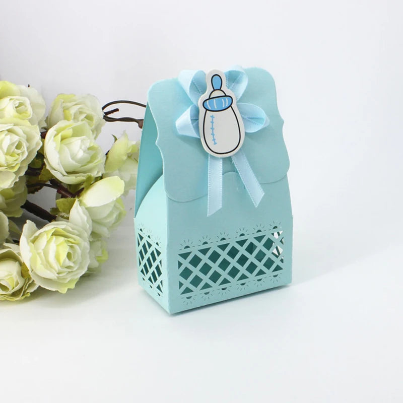 Light blue gift box with baby bottle design and bow, surrounded by white flowers on a light background