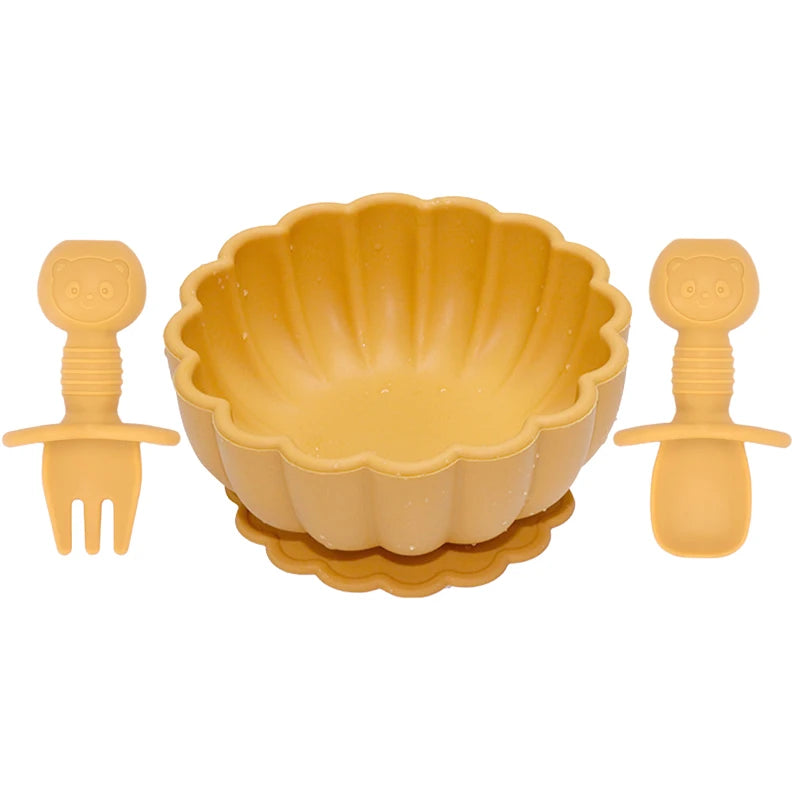 Yellow children's bowl set with fork and spoon on a white background